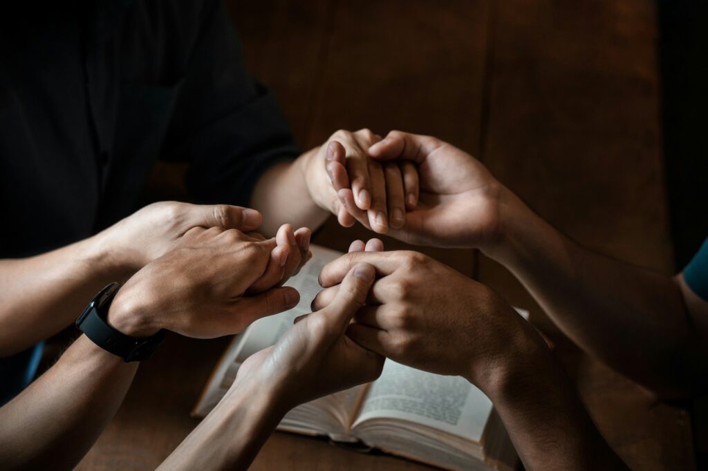 A group of young Christians holding hands in prayer for faith and scriptures